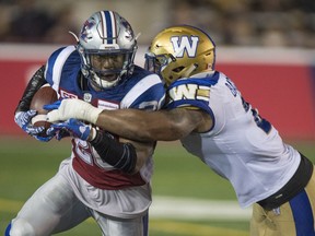 Alouettes running back Tyrell Sutton is tackled by Blue Bombers linebacker Khalil Bass on Friday, August 26, 2016 at Molson stadium. The team defended its decision to run Sutton out of the shotgun formation on a failed third-and-1 attempt.