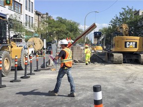 Work on the east side of St. Denis St. has been completed, and the west side is half done, with the project still on time. Rachel St. was closed on Sunday night for about a week to cars. Bikes and pedestrians can still cross. In this photo, a construction worker carries a detour sign during construction work on St-Denis St. at the corner of Rachel in Montreal Monday Aug. 15, 2016.