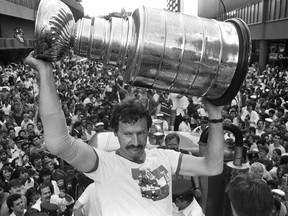 Montreal Canadiens Larry Robinson hoists the Stanley Cup, on Atwater St, for fans out front of the fabled Montreal Forum (at right) on Monday, May 26, 1986. An estimated 500,000 fans lined the parade route for about five hours for a chance to see the 1986 Stanley Cup winners.