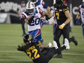 Montreal Alouettes running back Tyrell Sutton (20) runs over Hamilton Tiger-Cats defensive back Courtney Stephen (22) during the first half of CFL football action in Hamilton on Friday, September 16, 2016.