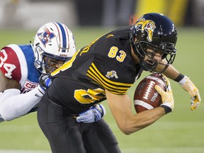 Montreal Alouettes linebacker Kyries Hebert (34) gets hold of the jersey of Hamilton Tiger-Cats wide receiver Andy Fantuz (83) during the first half of CFL football action in Hamilton on Friday, September 16, 2016.