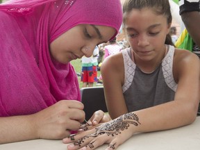 Yameen Bibi, left, applies henna tattoo on the hand of Tamrah Valiant during Vivre Ensemble multiculturalism day at Vinet Park on Saturday Sept.10, 2016.
