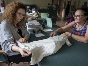 Textile historian Jennifer Millen left, examines a night dress on a 90-year-old doll owned by Adele Poupart right, of Dollard-des-Ormeaux during the Treasures in the Attic event in 2015.