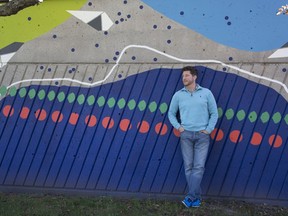 Paul Bassily, owner of Hawaii Ice, poses by the painted wall at the Valois station across from his ice cream shop in Pointe-Claire. Bassily and other merchants have concerns that important infrastructure issues (and graffiti) have been ignored, while over $25,000 was spent on artwork.