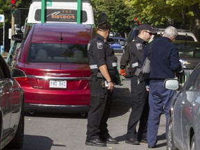 Montreal Taxi Bureau inspectors speak to an Uber driver after seizing his car on Berri St. in Montreal, Monday, Sept. 26, 2016.  Uber has challenged all the car seizures in Montreal Municipal Court.