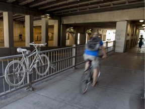 A cyclist rides past one of Montreal's "ghost bikes" that mark the spot where fatal accidents have occurred. This one is for Mathilde Blais, who was hit by a truck on the St-Denis St. underpass in Rosemont.