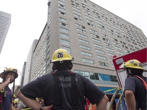 Montreal firefighters stand on René-Levesque W. Blvd. near the Queen Elizabeth hotel after a small fire was brought under control in the upper floors of the hotel on Thursday, Sept. 8, 2016. No injuries were reported. The hotel is closed during the renovations.