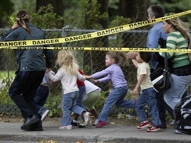 Public security personnel lead children down De Maisonneuve Blvd. away from a daycare on the Dawson College campus, where a gunman opened fire on students, Sept. 13, 2006.