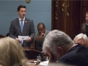 Coalition Avenir Quebec MNA Simon Jolin-Barrette, left, tables a petition before question period Wednesday, September 21, 2016 at the legislature in Quebec City. Quebec Premier Philippe Couillard, right foreground, touches his forehead.