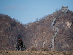A North Korean man rides his bicycle in front of a portion of the Great Wall on Hwanggumpyong Island, located in the middle of the Yalu River between the North Korean town of Sinuiju and the Chinese town of Dandong on February 9, 2016.