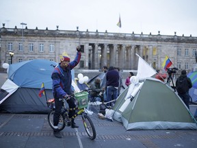 A cyclist raises his arm next to students camping to ask for peace at the main square in Bogota, Colombia, Oct. 7, 2016. Colombian President Juan Manuel Santos won the Nobel Peace Prize Friday, just days after Colombian voters narrowly rejected a peace deal he signed with rebels of the Revolutionary Armed Forces of Colombia, FARC.