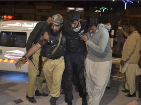 A Pakistani volunteer and a police officer rush an injured person to a hospital in Quetta, Pakistan, Monday, Oct. 24, 2016. A government official said tens of police trainees were killed when gunmen attacked a hostel at a police training centre in Pakistan's restive southwestern Baluchistan province.