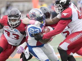 Alouettes running back Brandon Rutley is tackled by Calgary Stampeders' Micah Johnson, left, and Cordarro Law, right, during first quarter CFL football action, Sunday, Oct. 30, 2016, in Montreal.
