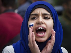 A girl wearing an al-amira hijab takes part in a demonstration opposing the proposed Charter of Quebec Values by the Parti Québécois government led by Pauline Marois in downtown Montreal on Saturday, Sept. 14, 2013.