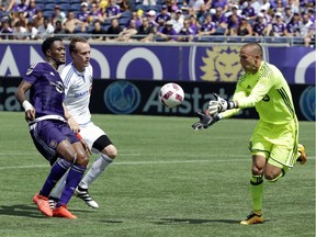 Montreal Impact goalkeeper Evan Bush, right, makes a save in front of teammate midfielder Wandrille Lefèvre, centre, and Orlando City's Cyle Larin, left, during the first half of an MLS soccer game, Sunday, Oct. 2, 2016, in Orlando, Fla.