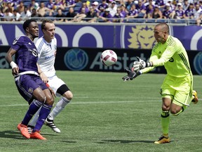 Montreal Impact goalkeeper Evan Bush, right, makes a save in front of teammate midfielder Wandrille Lefevre, centre, and Orlando City's Cyle Larin, left, during the first half of an MLS soccer game, Sunday, Oct. 2, 2016, in Orlando, Fla. (AP Photo/John Raoux)