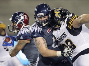 Montreal Alouettes offensive-lineman Jacob Ruby blocks Hamilton Tiger-Cats Michael Atkinson as he protects quarterback Vernon Adams Jr., left, during Canadian Football League game in Montreal Friday July 15, 2016.