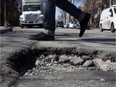 A pedestrian walks by a massive pothole in the Plateau. The resurfacing of Montreal's roads could take $415 million of the proposed capital-works spending program.
