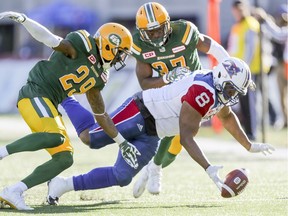Montreal Alouettes' Nik Lewis dives for the football that he fumbled after making a catch, pursued by Edmonton Eskimos Cord Parks, left, and Kenny Ladler  during CFL action at Molson Stadium in Montreal on Monday, Oct. 10, 2016.