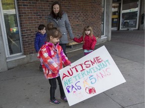 Five-year-old Simone Kühn carries a placard as she, her twin sister Charlotte, left, their mother Lynn Buchanan and younger sister Anna, 4, stage a short family protest outside the Place St. Henri metro station in Montreal, Wednesday October 26, 2016. The family was trying to draw attention to the fact that Charlotte, who is autistic, is still waiting for access to publicly funded speech therapy.