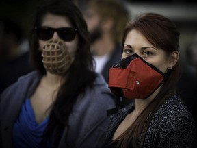Maude Deshies left and Shanelle Foucault right, wear muzzles during a protest against Montreal's pit-bull bylaw, Oct. 4, 2016.