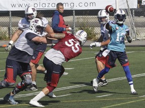 Montreal Alouettes quarterback Rakeem Cato makes a pass as offensive lineman Jeff Perrett (left) clears away pass rushers Gabriel Knapton during  practice at Stade Hébert in Montreal Thursday, October 6, 2016. Behind is head coach and wide receivers coach Jacques Chapdelaine.
