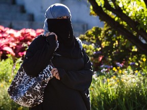 The niqab is not a common sight in Montreal. Here, a woman wearing a niqab waits to cross the street in front of the George-Étienne Cartier Monument in Montreal on Tuesday, September 17, 2013.