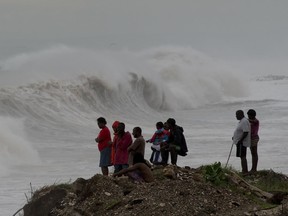 People stand on the coast watching the surf produced by Hurricane Matthew, on the outskirts of Kingston, Jamaica, Oct. 3, 2016.