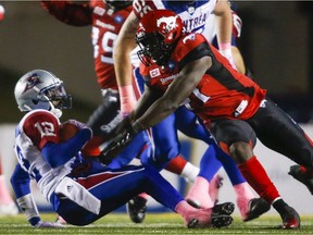 Alouettes quarterback Rakeem Cato, left, is knocked to the field by Calgary Stampeders' Cordarro Law in Calgary on Saturday, Oct. 15, 2016.