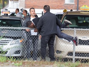 Taxi drivers help each other cross a fence to get to the assembly area for a taxi protest Oct. 5, 2016. Taxi drivers are on strike to protest the government deal with the Uber ride service.