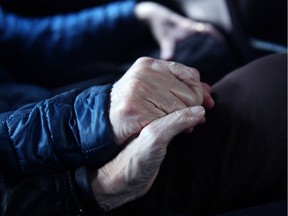 A terminal cancer patient holds hands with a family member.