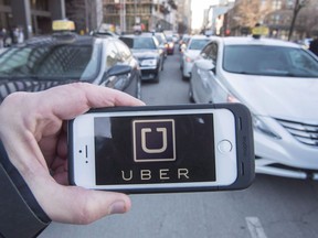 The Uber logo is seen in front of protesting taxi drivers at the Montreal courthouse, on February 2, 2016. Calgary city council has passed a bylaw that would allow for the operation of ride-sharing companies, but officials with Uber say the rules are too strict.