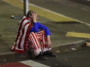 A man dressed in red-white-and-blue sits on the curb during a protest against President-elect Donald Trump, Nov. 9, 2016, in Seattle's Capitol Hill neighbourhood.