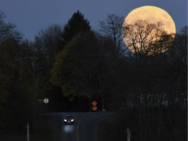 A vehicle travels down a road as the supermoon rises in Auburn, N.Y., Nov. 13, 2016. The phenomenon known as the supermoon will reach its most luminescent in North America before dawn on Monday.