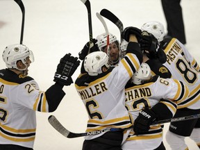 Boston Bruins' Brandon Carlo (25), Colin Miller (6) and David Pastmak (88) join other teammates to congratulate Jimmy Hayes after his game-winning goal over the Tampa Bay Lightning during a shootout in an NHL hockey game Thursday, Nov. 3, 2016, in Tampa, Fla.