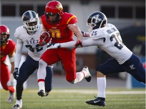 St. Francis Xavier X-Men's Mike Miller, left, and Justin Holland, right, tackle University of Calgary Dinos' Dallas Boath during first half U Sports Mitchell Bowl semifinal football action in Calgary, Saturday, Nov. 19, 2016.