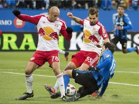 New York Red Bulls' Aurelien Collin (78) and Damien Perrinelle (55) challenge Montreal Impact's Ignacio Piatti during second half action of the first leg of the eastern conference MLS soccer semifinal in Montreal, Sunday, October 30, 2016.