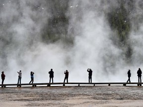 This file photo taken on May 11, 2016 shows  Tourists at the Grand Prismatic Springin Yellowstone National Park. Colin Nathaniel Scott, 23, of Oregon, accidentally fell into a hot spring on June 7, 2016, at Yellowstone National Park and died, was dissolved in the boiling acidic waters, according to a report made public on November 17, 2016.   /