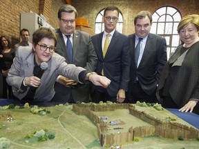 Archaeologist Louise Pothier, left, points to a scale model of Fort Ville-Marie, with from left, Montreal Mayor Denis Coderre; J.Serge Sasseville, a senior VP at Quebecor; Pointe-à-Callière Museum chair of the board Andrew Molson; and museum executive director Francine Lelievre during a news conference to present a heritage leagacy to mark Montreal's 375th anniversary in Montreal, Thursday, Nov. 24, 2016.