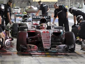 Mercedes driver Lewis Hamilton of Britain and teammate Nico Rosberg of Germany, in the background, pull into pit lane during practice for the Abu Dhabi Grand Prix at the Yas Marina racetrack.