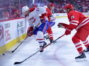 Torrey Mitchell of the Montreal Canadiens protects the puck from Jay McClement #18 and Matt Tennyson #26 of the Carolina Hurricanes during the game at PNC Arena on November 18, 2016 in Raleigh, North Carolina.