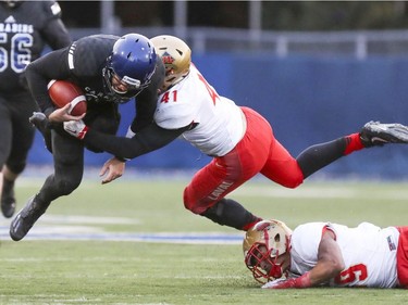 Carabins de Université de Montréal quarterback Pierre-Luc Varhegyi is tackled by Laval Rouge et Or's Cedric Lussier-Roy, 41, and Gabriel Marcoux during the Quebec university football championship game in Montreal on Saturday, Nov. 12, 2016.