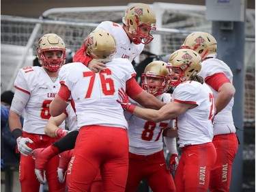 Laval Rouge et Or quarterback Hugo Richard jumps into the arms of team-mate Samuel Thomassin, 76, after a touchdown by team-mate Jonathan Breton-Robert, 87, during the Quebec university football championship game against the Carabins de Université de Montréal in Montreal on Saturday, Nov. 12, 2016.