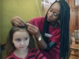 Marly Pericles braids Chloe Lessard's hair at a fundraising fair at Concordia University sponsored by Care Jeunesse.
