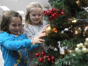 Four year-old Olivia Sampson, left, and her sister, Chloe, help decorate Christmas tree in the Plaza Pointe-Claire on Friday November 25, 2016. The event was part of the West Island Community Shares' Light Up the Community campaign. (Pierre Obendrauf / MONTREAL GAZETTE)