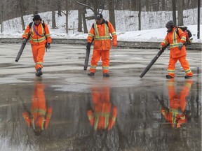City of Montreal workers (from left) Dominique Léger, Philippe Péloquin and Stéphanie Levac blow away dirt from the cement surface of the artificial skating rink at Beaver Lake will be in Montreal, Nov. 28, 2016.