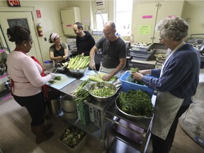 NDG Food Depot director Daniel Rotman (rear) speaks with community chef Amy Dramilarakis as volunteers, from  left, Cheryl Williams, Brian Lott and Larry Paul work in the kitchen of the Depot in Montreal Monday, Nov. 28, 2016.