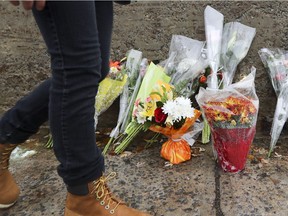 A young man walks by a makeshift memorial in 2016 for a teenage boy who was stabbed to death on L'Ile-des-Soeurs Blvd. on Nuns' Island in Montreal.