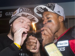 Ottawa Redblacks kicker Chris Milo, left, and quarterback Henry Burris light cigars as they celebrate defeating the Calgary Stampeders for the Grey Cup win, Nov. 27, 2016 in Toronto.
