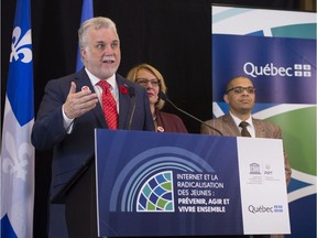 Quebec Premier Philippe Couillard speaks to reporters at a news conference on youth radicalization, as part of a UNESCO conference on radicalization, in Quebec City on Tuesday, November 1, 2016. Christine St-Pierre, Quebec minister of International Relations and La Francophonie, looks on.